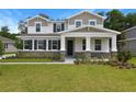 Inviting two-story house featuring stone details, a covered entrance, and lush green grass at 3725 Deer Ridge Dr, Mount Dora, FL 32757