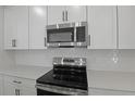 Contemporary stainless steel microwave and electric range stand above white quartz countertops and backsplash at 3725 Deer Ridge Dr, Mount Dora, FL 32757