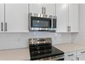 Close up view of white quartz countertops and stainless steel appliances at 3757 Deer Ridge Dr, Mount Dora, FL 32757