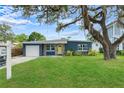 Inviting single-story home with a green lawn and a yellow front door under a large tree at 4217 Park Lake St, Orlando, FL 32803