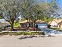 Exterior view of home with trees on a large lot with a two car garage and a well manicured lawn at 4222 Gold Rush Ln, St Cloud, FL 34772