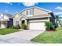 Charming home features a lush green lawn and a brick driveway leading to an attached two-car garage, perfect for families at 509 Cadiz Loop, Davenport, FL 33837