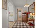 Welcoming entryway with a checked rug, a stylish hall tree, and views of the adjacent kitchen at 6475 Peppertree Ne Path, Winter Haven, FL 33881