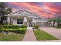 Charming single-story home with a well-manicured lawn, a brick walkway, and a three car garage at 11454 Wakeworth St, Orlando, FL 32836