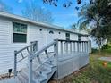 Exterior of a well-maintained home featuring white siding, a gray porch and stairs, and a green lawn at 18633 14Th Ave, Orlando, FL 32833