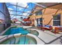 Relaxing screened-in pool area with in-ground jacuzzi, outdoor furniture, and a canopy providing shade perfect for entertaining guests at 413 Paloma Dr, Davenport, FL 33837