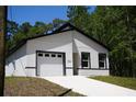 Modern, newly constructed single-story home with a bright white exterior, dark trim and an attached garage at 6862 Se 23Rd Ave, Ocala, FL 34480