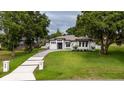 Beautiful single-story home with a well-manicured lawn and a long, grand driveway lined with trees at 13049 Sunshine Cir, Clermont, FL 34711
