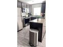 Kitchen featuring stainless steel appliances, granite counters, and wood grain floors at 1919 Escambia Ln, Kissimmee, FL 34759