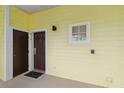 A ground floor condo entrance featuring a brown door and a small square window allowing for natural light at 313 Lucaya Loop # 313, Davenport, FL 33897
