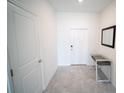 Hallway featuring a glass-topped table, a mirror, and neutral colored tile flooring at 4211 Little Owl Ln, Kissimmee, FL 34746