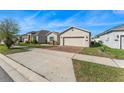 A single-Gathering home offers a brick driveway, well-kept lawn, and an attached two-car garage at 485 Disa Dr, Davenport, FL 33837