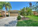 Traditional home featuring a brick driveway, two-car garage, and vibrant landscaping, creating a welcoming curb appeal at 555 Presido Park Pl, Kissimmee, FL 34759
