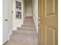 Carpeted staircase illuminated by natural light, complemented by modern artwork and a freshly painted wall at 7128 Red Lantern Dr # 0, Harmony, FL 34773