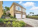 Beautiful exterior view of a two-story home with a brick driveway and lush landscaping at 7623 Excitement Dr, Reunion, FL 34747