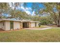 Charming single-story home boasts a stone facade and well-manicured lawn, nestled under mature trees at 1590 Twelve Oaks Cir, Kissimmee, FL 34744