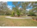 Charming single-story home featuring a circular driveway surrounded by mature trees and lush landscaping at 1590 Twelve Oaks Cir, Kissimmee, FL 34744