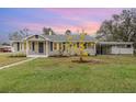 Charming single-story home with a well-maintained lawn and a covered carport, all under a beautiful sunset sky at 2237 Avenue B Nw, Winter Haven, FL 33880