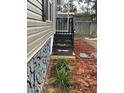 Side view of home with rock skirting, a stairway, and beautifully maintained landscape at 34517 Laralack Ave, Leesburg, FL 34788