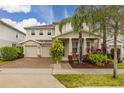 Inviting two-story home with lush landscaping, mature palms, and brick-paved driveway at 5685 Surprise Lily Dr, Winter Garden, FL 34787