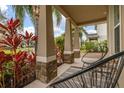 Inviting front porch with decorative columns, stone accents, and comfortable outdoor seating at 5685 Surprise Lily Dr, Winter Garden, FL 34787