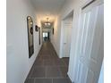 Long, bright hallway featuring modern tile flooring, white walls, and stylish light fixtures at 676 Tanaro Ln, Haines City, FL 33844