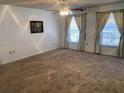 Spacious living room with carpet flooring and two windows dressed with curtains at 706 Francis St, Kissimmee, FL 34741