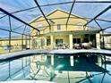 Screened pool reflects the yellow two-story home with covered patio seating and an outdoor kitchen at 1201 Providence Blvd, Kissimmee, FL 34744