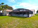 Backyard view featuring a screened-in enclosure attached to the house and lawn at 2235 Emperor Dr, Kissimmee, FL 34744