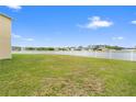 Expansive backyard featuring a vinyl fence, lush green grass, and a view of the pond at 2412 Country Pond Ct, St Cloud, FL 34771