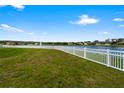 Lush green backyard featuring a white vinyl fence and a view of a peaceful lake at 2412 Country Pond Ct, St Cloud, FL 34771