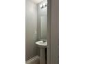Powder room featuring a pedestal sink, mirror and modern light fixture at 49 Inconnu Dr, Poinciana, FL 34759