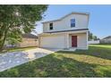 Inviting two-story home featuring a red front door, attached garage, and a well-maintained lawn at 49 Inconnu Dr, Poinciana, FL 34759