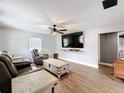 Comfortable living room featuring hardwood floors, a ceiling fan, and a large flat-screen TV at 521 Florida Ave, St Cloud, FL 34769