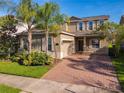 Two-story home with a brick-paved driveway, well-manicured landscaping, and a two-car garage at 15129 Driftwood Bend St, Winter Garden, FL 34787