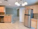 Bright kitchen with stainless steel fridge, wood cabinets, and view into the living area at 181 Whisper Wood Ct, Kissimmee, FL 34743