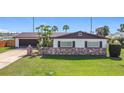 Inviting home features a charming stone accent wall, mature palm trees, and well-maintained green lawn at 2512 Virginia Dr, Kissimmee, FL 34741