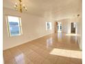 Spacious living room featuring tile floors, classic chandelier, and multiple windows, creating a bright atmosphere at 296 Sand Ridge Dr, Davenport, FL 33896