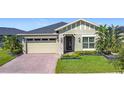 Charming one-story home featuring stone accents, a brick driveway, and lush tropical landscaping at 3240 Songbird Cir, Harmony, FL 34773