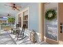 Inviting front porch with rocking chairs, ceiling fans, and decorative wreath on front door at 3308 Cat Brier Trl, Harmony, FL 34773