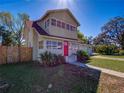 Charming two-story home boasting a red front door, mature trees, and an attached garage at 103 W Maple St, Davenport, FL 33837