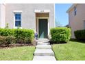 Inviting front entrance featuring a green door, concrete steps, and manicured shrubs at 1615 Reflection Cv, St Cloud, FL 34771