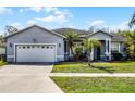 A single-story home has a well-manicured lawn with palm trees and a 2 car garage on a sunny day with blue skies at 2539 Jasmine Trace Dr, Kissimmee, FL 34758