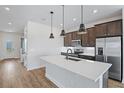 Modern kitchen features a large island with quartz countertop, stainless steel appliances, and stylish pendant lighting at 276 Hilltop Bloom Loop, Haines City, FL 33844