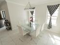 Bright dining room with a modern glass table, white chairs, and stylish black curtains at 2804 Alpine Meadow Ln, Kissimmee, FL 34744