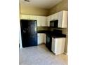 Functional kitchen featuring white cabinetry, black appliances, and durable tile flooring at 2981 Winding Trl, Kissimmee, FL 34746