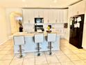 Bright kitchen boasts white cabinetry, modern appliances, island with seating, and tiled floors at 3082 Royal Tern Dr, Winter Haven, FL 33881