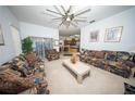Bright living room featuring a ceiling fan, patterned sofas, and a view into the kitchen area at 466 Peppermill Cir, Kissimmee, FL 34758