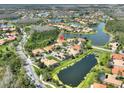 Expansive aerial view of a residential area with several small lakes and lush greenery, with roof highlighted in red at 1233 Cambria Bnd, Kissimmee, FL 34759