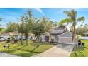 Well-kept single-story home with lush green lawn and mature trees, complemented by solar panels at 1437 Swift Ct, Kissimmee, FL 34759